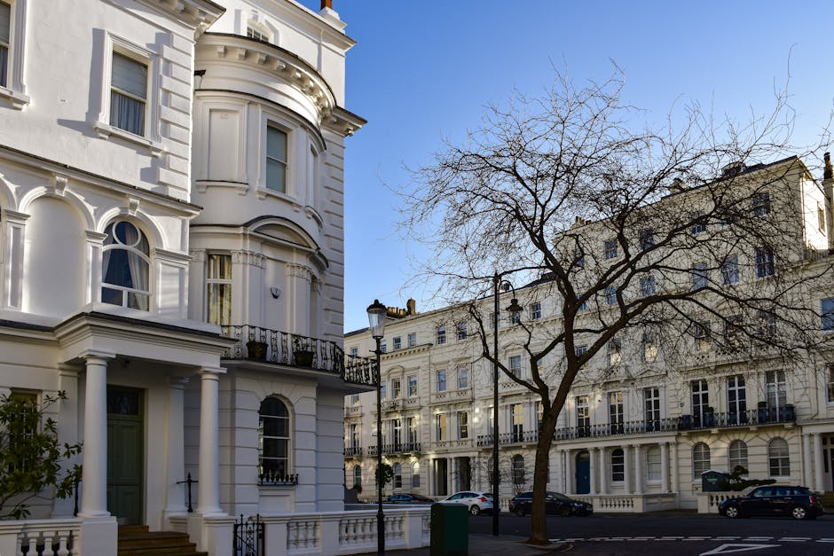 Exterior view of a historic multi-story building with ornate architectural details, cream-colored facade, and multiple large windows. A traditional black street lamp is positioned in front of the buil