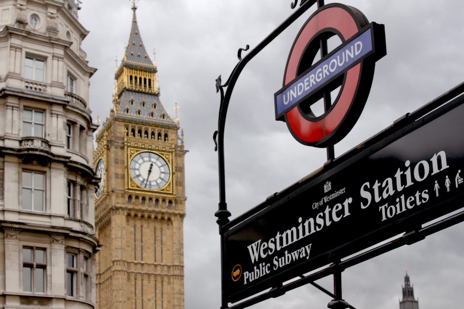A detailed close-up view of the clock face on the iconic Big Ben tower in Westminster, London, taken from a slightly lower angle through a narrow opening framed by dark stone arches. The clock shows 7